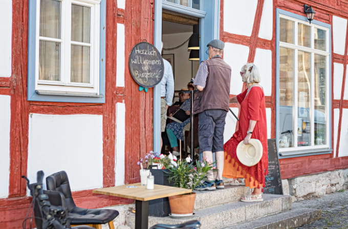 Fachwerkhäuser am Marktplatz von Ummerstadt, davor Gäste an Biertischen vor dem Bürgercafé